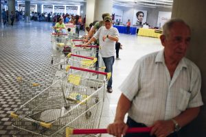 Customers line up to get in for shopping at a state-run Bicentenario supermarket in Caracas May 2, 2014. President Nicolas Maduro is introducing a controversial shopping card intended to combat Venezuela's food shortages but decried by critics as a Cuban-style policy illustrating the failure of his socialist policies. Maduro, the 51-year-old successor to Hugo Chavez, trumpets the new "Secure Food Supply" card, which will set limits on purchases, as a way to stop unscrupulous shoppers stocking up on subsidized groceries and reselling them. REUTERS/Jorge Silva (VENEZUELA - Tags: POLITICS BUSINESS SOCIETY TPX IMAGES OF THE DAY)