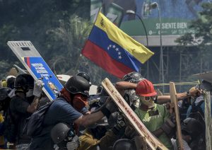 Opposition activists and riot police clash during a protest against President Nicolas Maduro in Caracas, on May 10, 2017. Venezuelan protesters hit the streets on Wednesday armed with "Poopootov cocktails," jars filled with excrement which they vowed to hurl at police as a wave of anti-government demonstrations turned dirty. / AFP PHOTO / CARLOS BECERRA