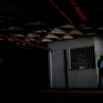 A private security guard stands close to the entrance of a parking garage during a blackout in Caracas